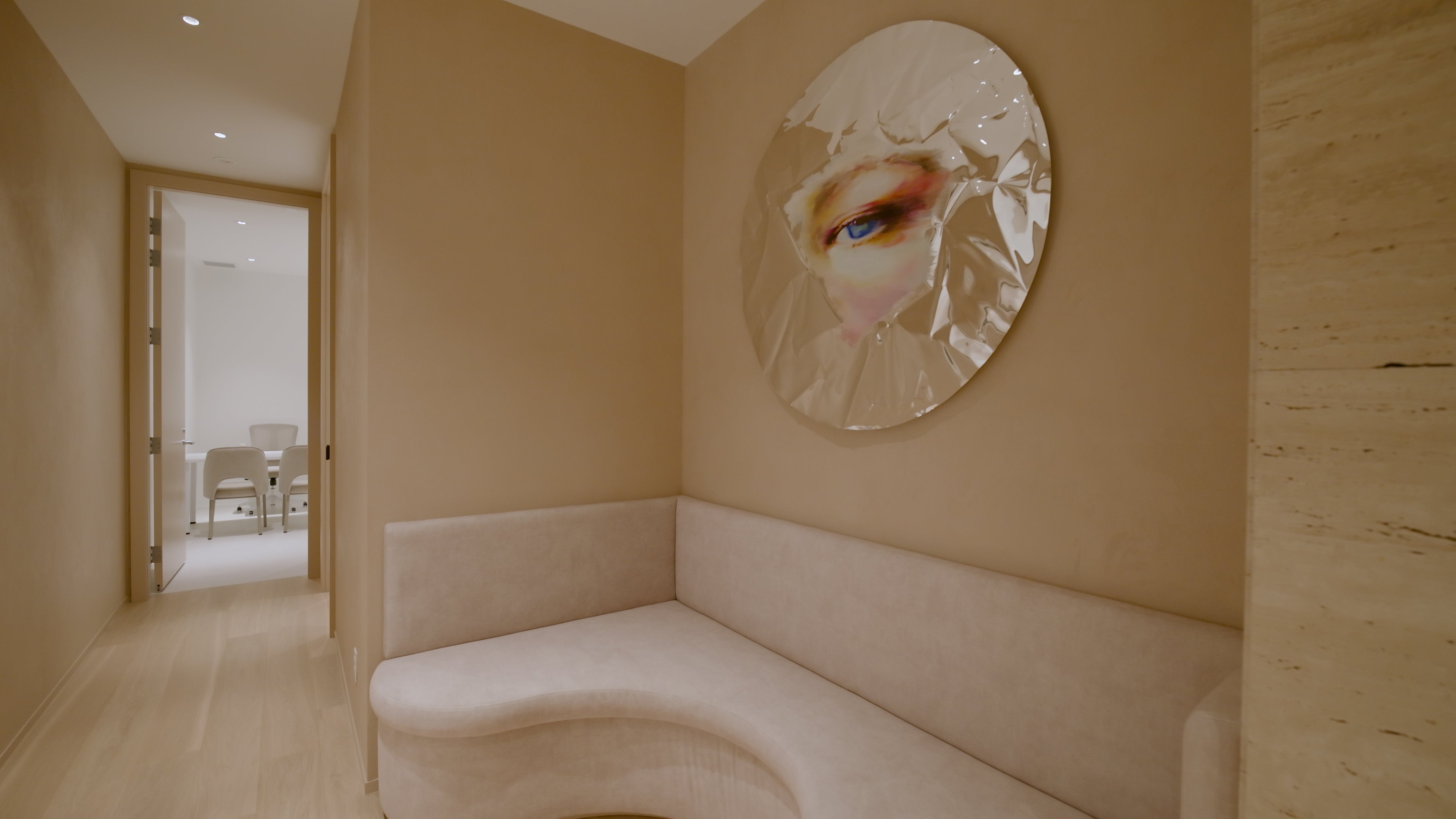 Beige room with a round mirror on the wall featuring an artistic depiction of a face.