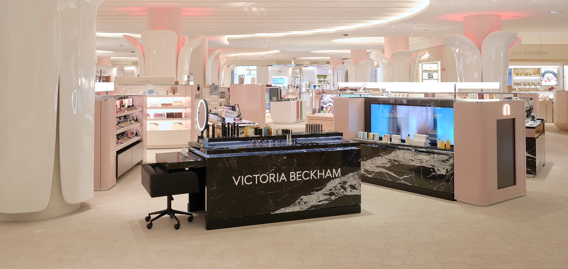 Victoria Beckham makeup display in a store with pink and white decor.